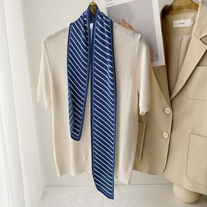 Detail of navy blue and white striped pleated scarf showing texture on white knitwear