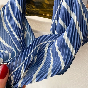 Macro shot of blue and white striped pleated fabric texture on a long skinny scarf