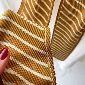 Detailed macro view of ginger yellow and white striped pleated scarf texture