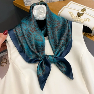 Silk square scarf with blue Paisley patterns and camellia accessory on white top