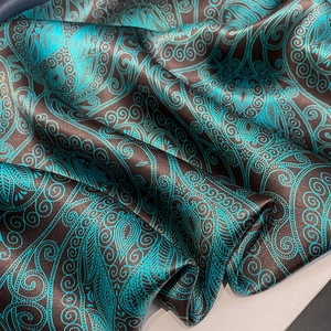 Close-up of silk scarf with brown background and green paisley pattern texture