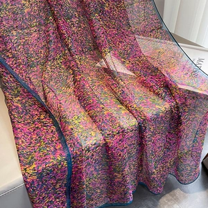 Détail d'un châle de plage d'été imprimé avec motif pointilliste sur chaise en cuir