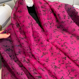 Détail d'une écharpe en mousseline rose fuchsia avec motifs floraux violets fins