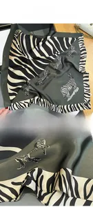 Detailed view of dark green silk scarf with zebra pattern border and fine stitched edges