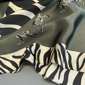 Close-up of zebra pattern silk scarf with dark green base and elegant silk texture