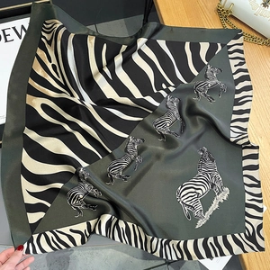 Detailed shot of dark green and zebra print silk scarf on a wooden table with props