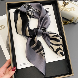 Zebra print silk scarf in grey and black, styled as a bow tie on a fashion magazine