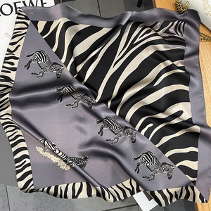 Detail shot of silk square scarf featuring realistic zebra print and animal motif borders