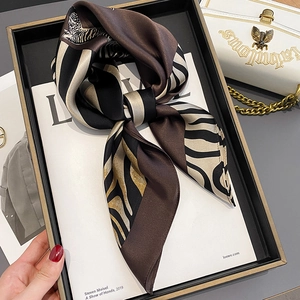 Fashionable silk scarf with animal print pattern displayed on a magazine and white handbag