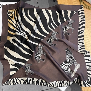 Close-up of silk square scarf with zebra print and brown borders on lifestyle background