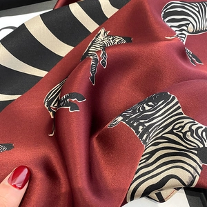 Macro shot of silk scarf showing glossy wine red fabric texture and zebra print pattern