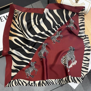Detailed close-up of burgundy zebra print silk scarf with luxury smooth satin texture