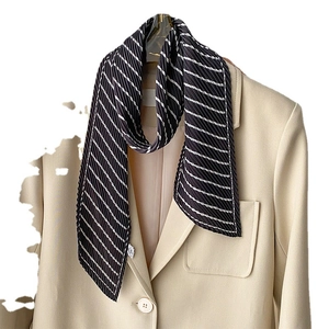 Chic black and white striped pleated scarf accessory styled on a beige blazer