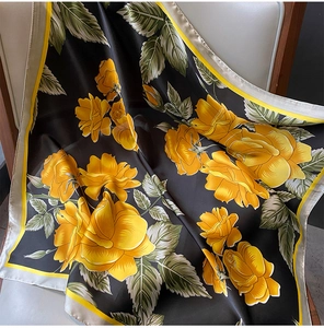 Detail of silk satin square scarf featuring yellow rose prints on a black background