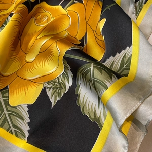 Close-up of silk scarf featuring vibrant yellow roses on a black floral print background