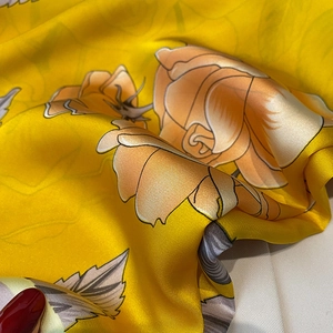 Detailed macro view of yellow silk satin fabric with realistic orange rose floral print