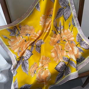 Close-up of yellow silk square scarf with realistic orange roses and lilac border decor