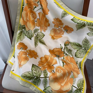 Detailed macro view of orange rose floral silk scarf on a wooden chair cushion