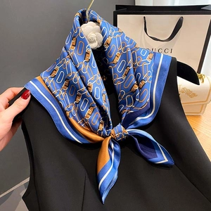 Blue and gold silk scarf with chain pattern and letter prints styled on black clothing