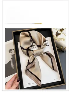 Detail of silk square scarf in champagne gold with brown striped hem tied in a knot