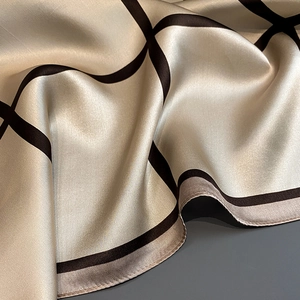 Detail view of champagne silk scarf with brown geometric plaid pattern and satin texture