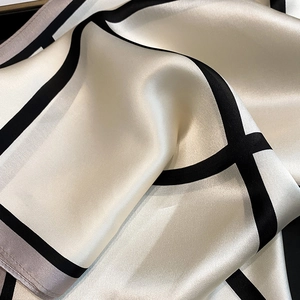 Detailed view of luxury geometric silk scarf texture with elegant satin finish and edges