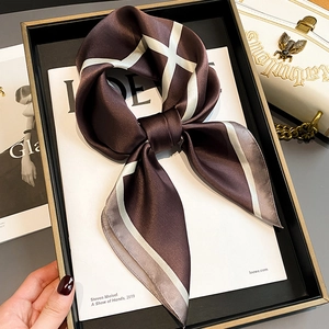 Brown silk scarf with geometric checkered pattern tied in a bow on a fashion magazine