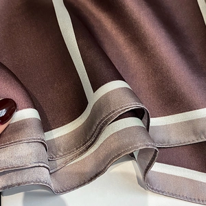 Detailed texture of silk square scarf with geometric lines and smooth satin finish
