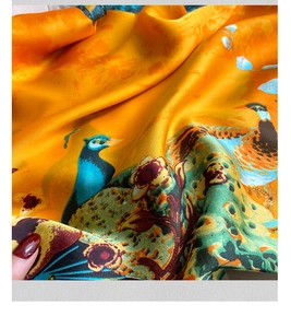 Dettaglio di foulard in seta satinata con stampa pavone e fiori in giallo e arancio