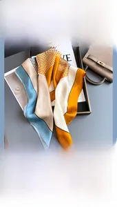 Silk scarf with geometric color block patterns and polka dots on a leather handbag