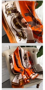 Detail of silk scarf with vintage carriage print draped on a beige sofa with a handbag