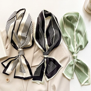 Dettaglio di tre foulard di raso a righe su un blazer beige con elementi decor