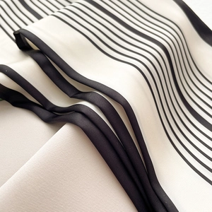 Dettaglio di un foulard in seta a righe bianche e nere con finitura satinata e cuciture fini