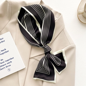 Sciarpa di seta classica a righe bianche e nere abbinata a un blazer beige elegante