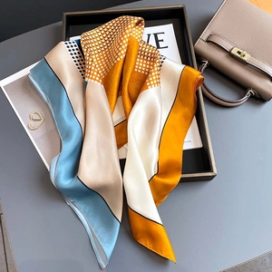 Silk square scarf with geometric blue and beige patterns and polka dots on a table