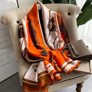 Long silk satin scarf with classical prints draped over a sofa in a luxury setting