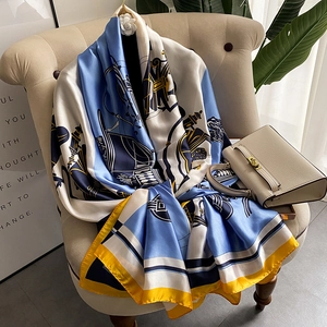 Long satin silk scarf with blue horse carriage print draped on an armchair