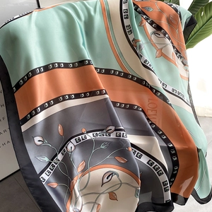 Floral block silk scarf with mint and orange colors hanging elegantly on a display