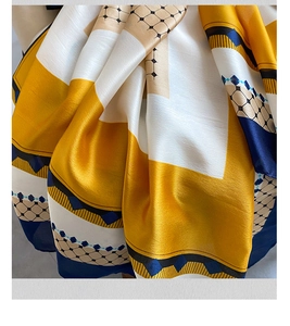 Close-up of silky yellow and blue geometric scarf showing fabric texture and drape