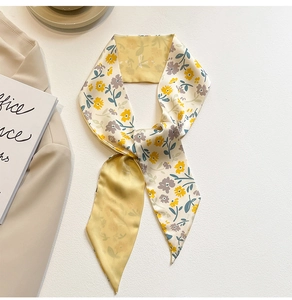 Détail d'un foulard en soie à fleurs noué comme accessoire sur une veste chic
