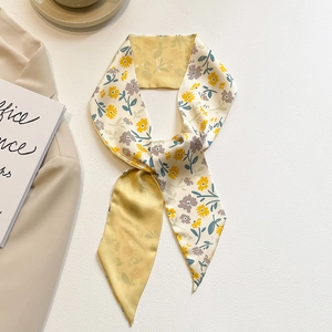 Détail d'un foulard en soie élégant à fleurs jaunes et violettes sur fond crème