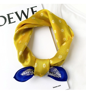 Detail of silk scarf with yellow daisy print and blue paisley pattern tied in a soft loop