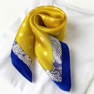 Macro detail of yellow silk scarf with paisley pattern on white t-shirt background