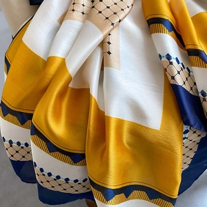 Luxurious yellow silk satin scarf with geometric patterns and soft elegant drapes