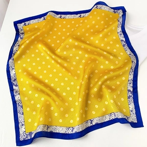 Detail of silk square scarf featuring yellow polka dots and blue paisley patterns