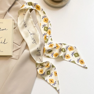 Détail du foulard en soie fleurie avec texte sur fond de veste de costume beige