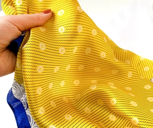 Close-up of bright yellow silk scarf with small white flowers and paisley patterns