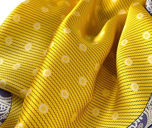 Macro shot of silk scarf with yellow daisy floral print and navy paisley detail