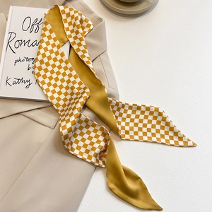 Détail d'un foulard en soie à damier jaune gingembre posé sur un costume beige chic