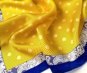 Detailed view of silk scarf featuring yellow floral patterns and blue paisley borders